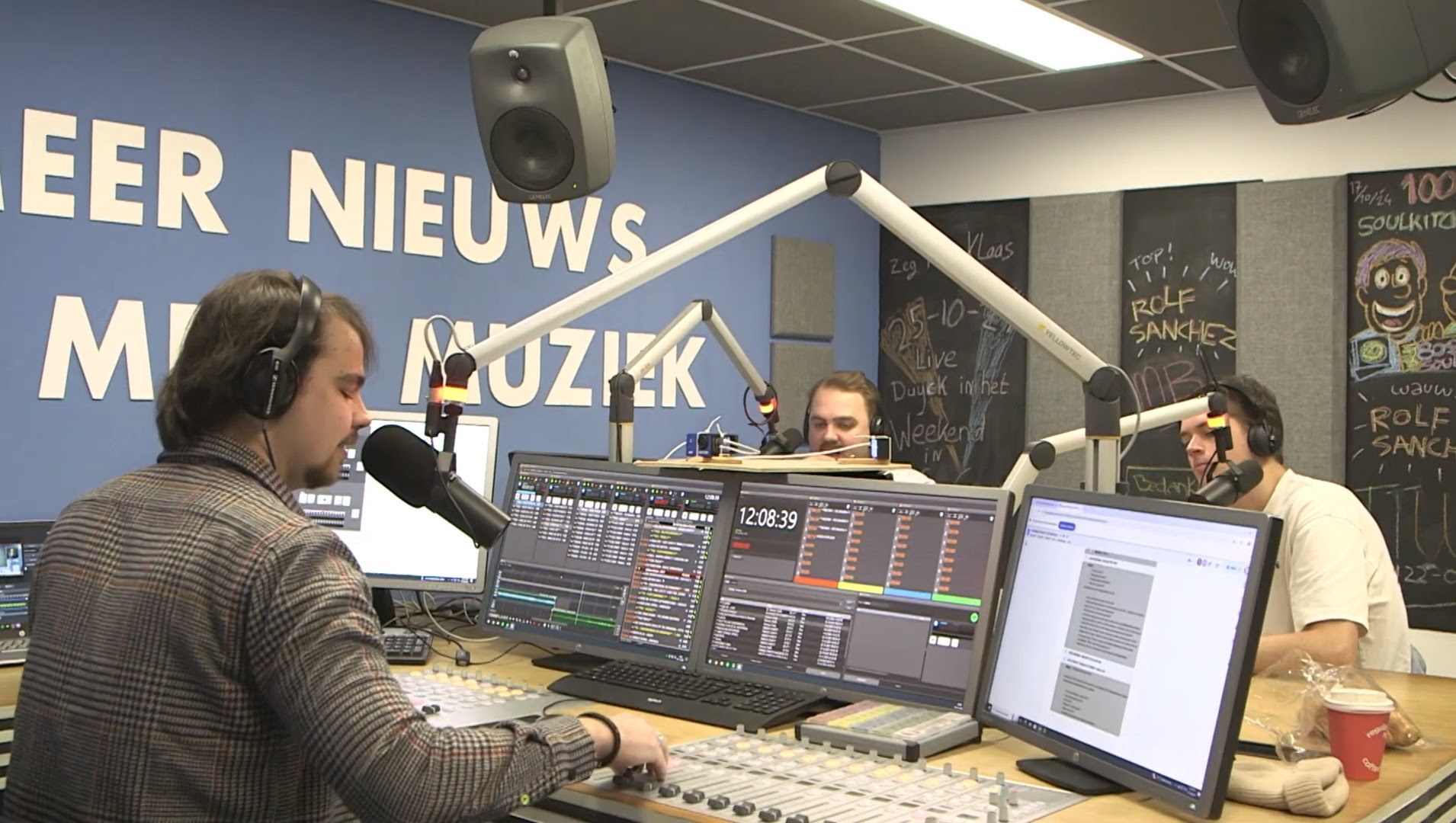 Drie presentatoren achter microfoons en mengtafel in de radiostudio van MeerRadio